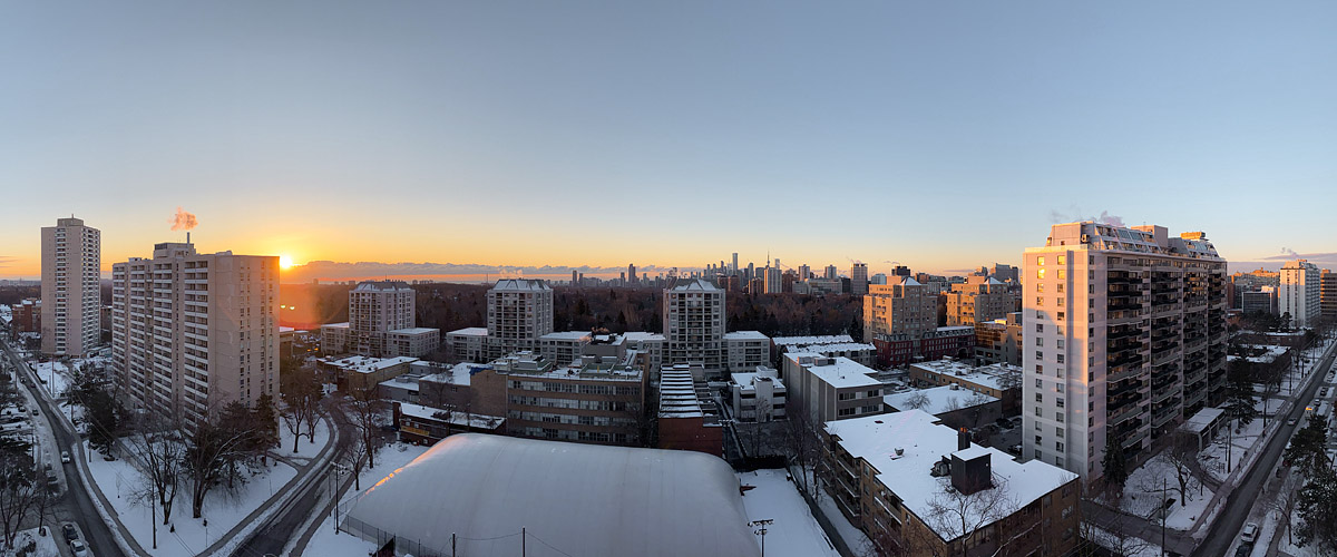 A clear sky with the sun just above the horizon, a narrow band of gold along the skyline and snow lying white below.