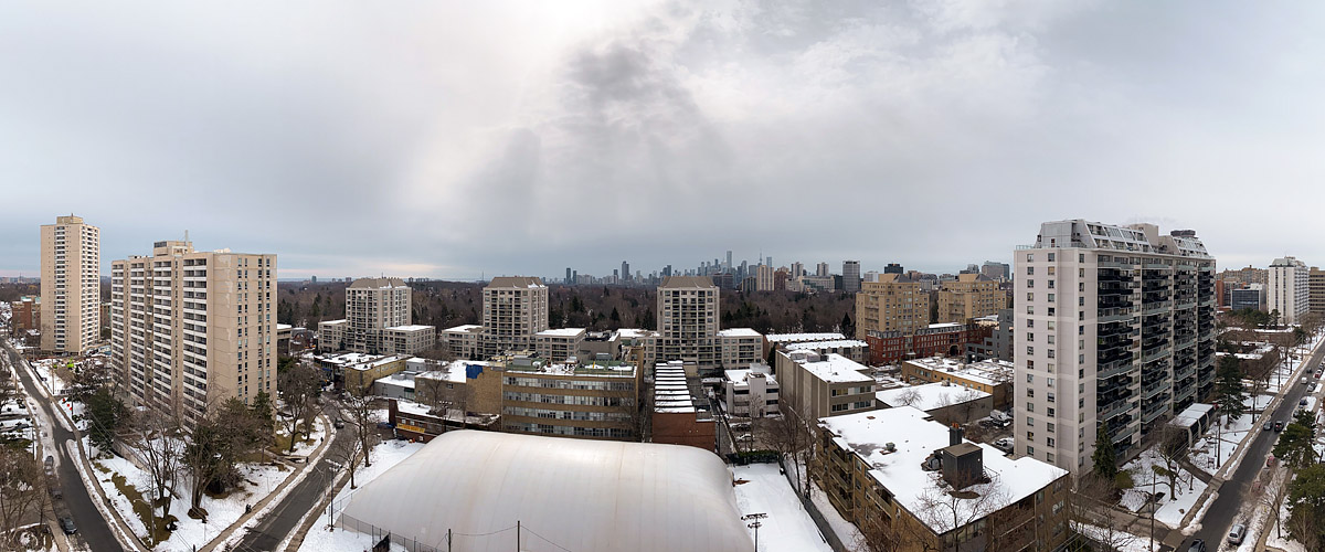 Grey cloud covers the sky with a dark ragged shower trailing streaks of snow over the middle distance, the skyline legible.