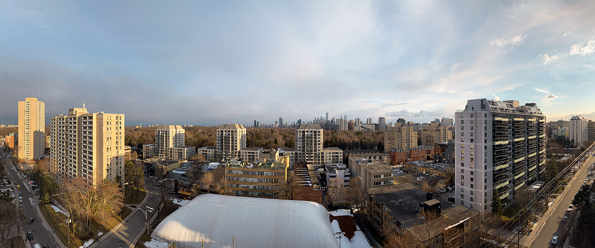 Thin broken cloud over a pale blue sky, low light on the tower faces and patches of old snow on the ground.