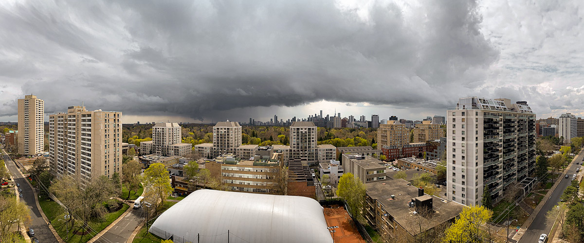 A dark storm shelf lies low across the sky above the skyline with pale light beneath its leading edge.