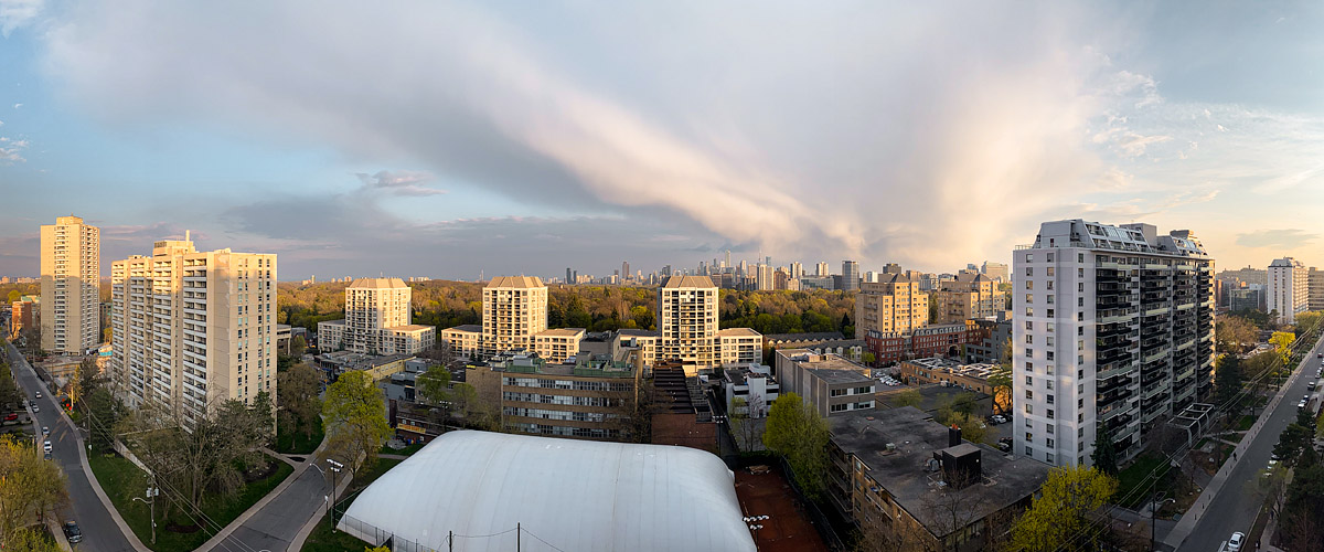 A long streaked cloud band lit warm by the low sun runs across the sky with blue above and below it.