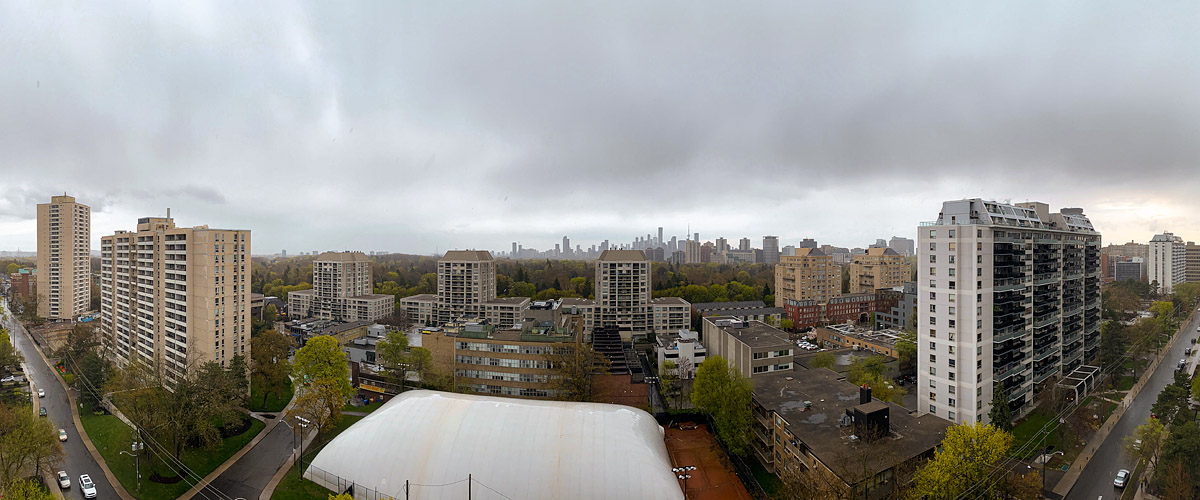 Uniform grey cloud over the whole sky, the skyline legible in flat light and the ground wet below.