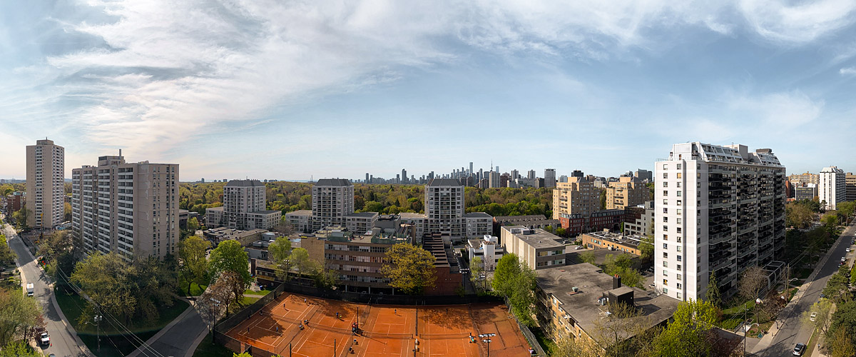 Thin streaked cloud across a pale blue sky, the skyline clear and the clay courts open and in use.