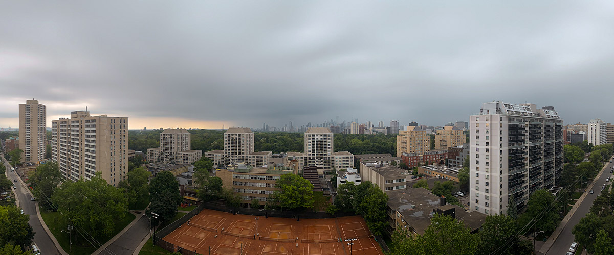 A flat grey cloud deck with rain in the air, the skyline a soft outline and the clay courts dark and wet.