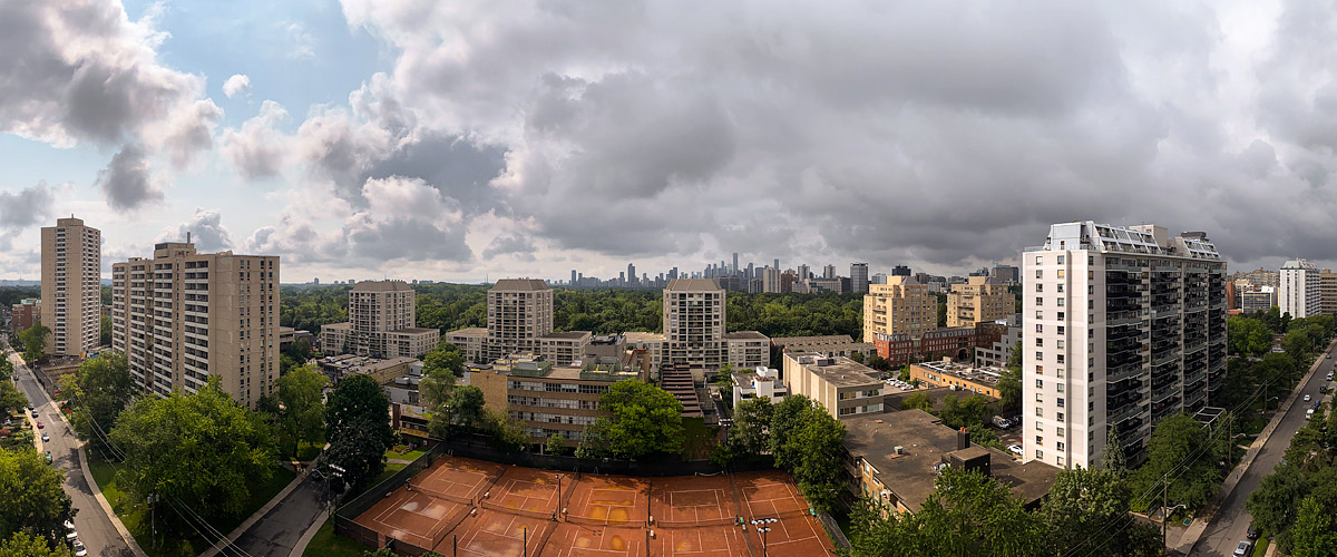 Broken grey cloud with blue showing at the left, the skyline visible and the courts dark and wet.