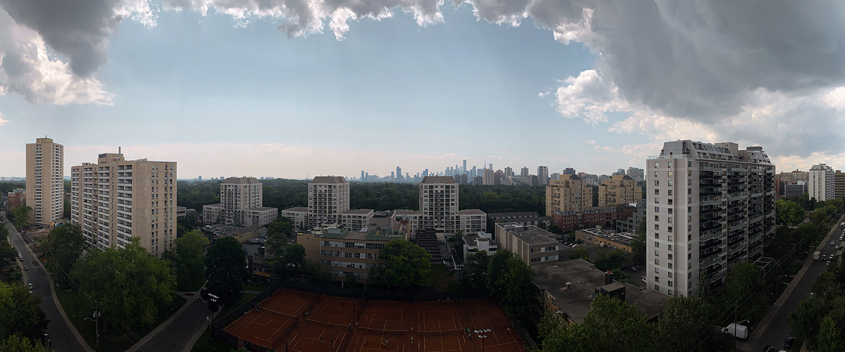 Dark cloud masses at both edges of the frame with pale hazy sky between them and a soft skyline.