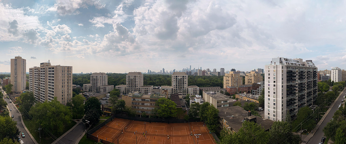 Broken grey and white cloud with blue gaps, the skyline soft behind a hazy horizon.