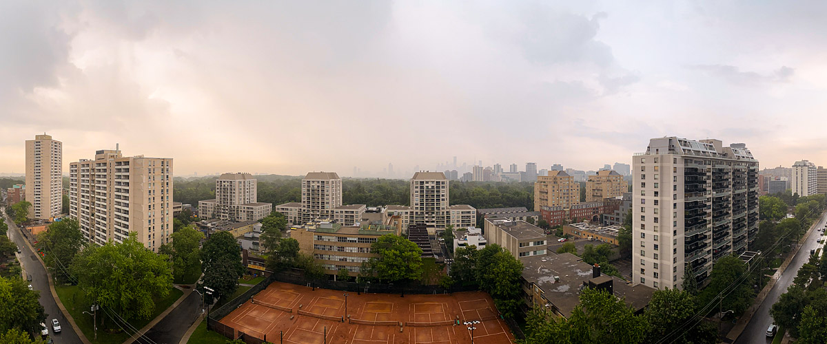Rain and warm murk dissolve the skyline into pale pink grey, the courts dark and wet below.