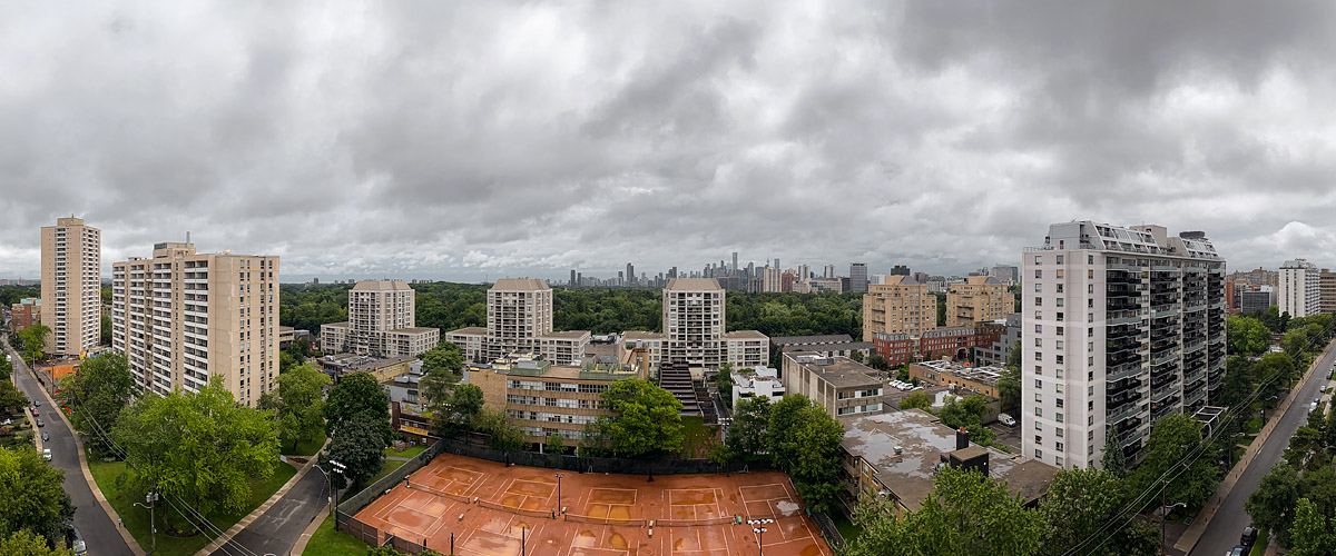 A uniform grey cloud deck over the whole frame, the skyline legible in flat light and the courts wet.