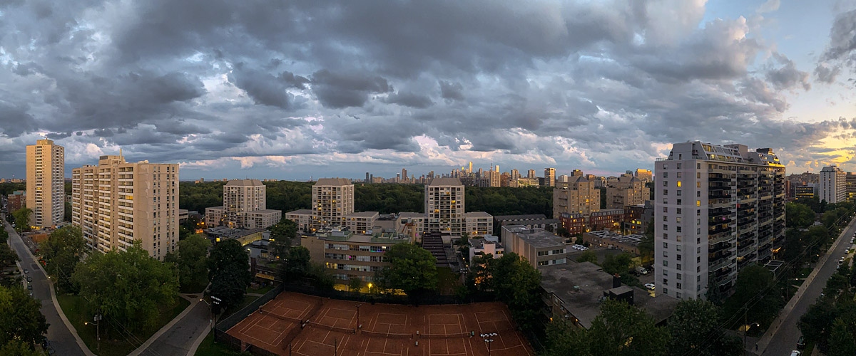 Heavy broken cloud with a warm break at the right edge and the city lights on.