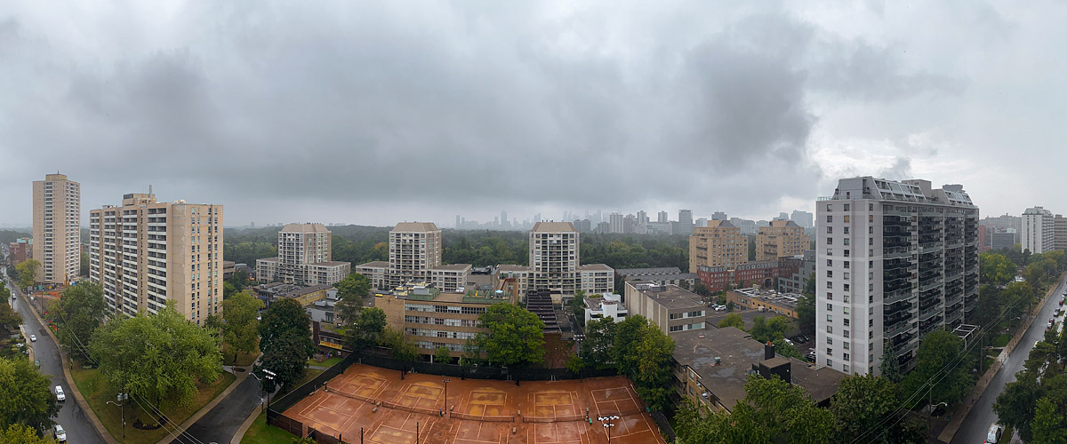 Dark grey cloud covers the sky with rain falling, the skyline soft and the courts wet.