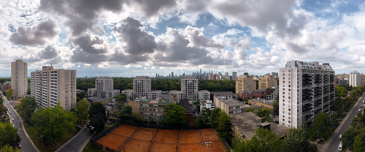 Broken grey and white cloud with blue between, the skyline clear and the clay courts busy below.