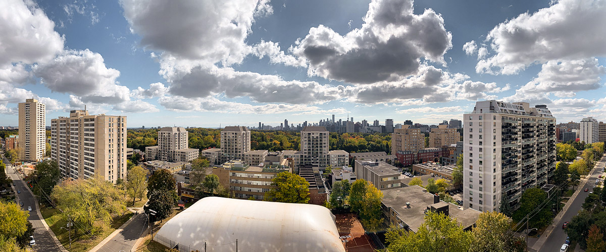 Bright cumulus across a deep blue sky, autumn colour through the canopy and the dome up over the courts.