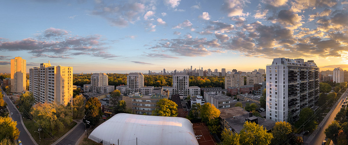 Small clouds lit gold and pink across a blue sky with a bright band at the right horizon.