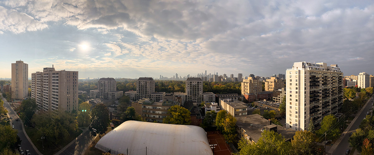 A textured deck of broken cloud with the sun showing through on the left and autumn colour in the canopy.