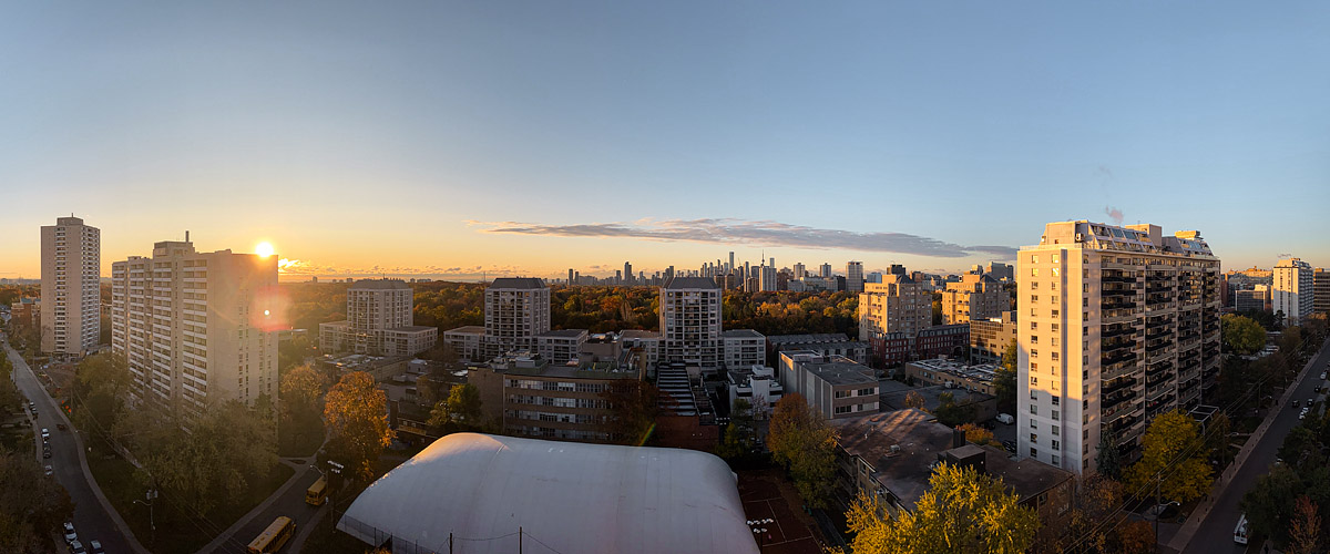 Clear sky with the sun just above the horizon at the left and a wide gold band behind the skyline.