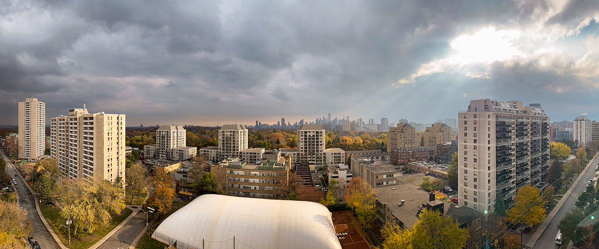 Heavy dark cloud covers most of the sky with a bright break at the right and rays fanning down over the towers.