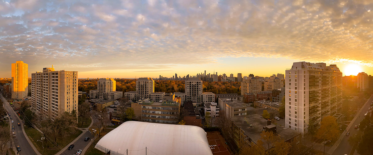 A rippled cloud deck lit gold across the whole sky with the sun on the horizon at the right.
