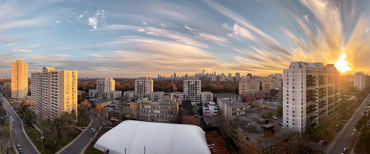 Sweeping fans of high cloud lit gold with the sun low at the right and blue on the left.