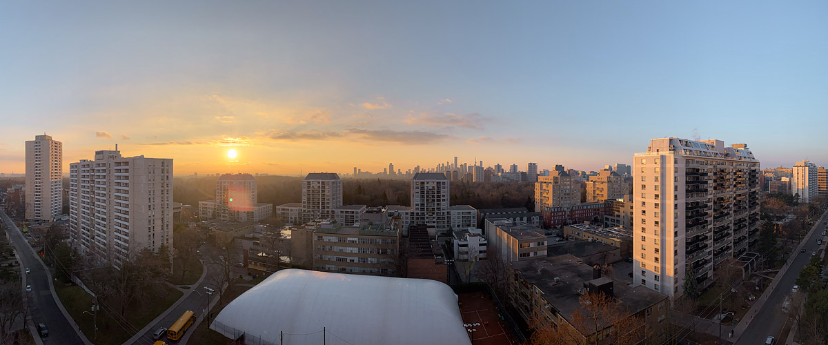 Clear sky with the low sun and a broad gold band above a murky horizon, the skyline soft behind it.