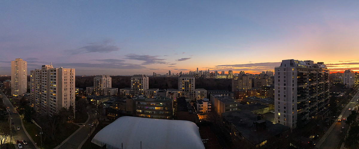 A mauve to orange gradient fills the sky above a dark skyline with the city lights on.