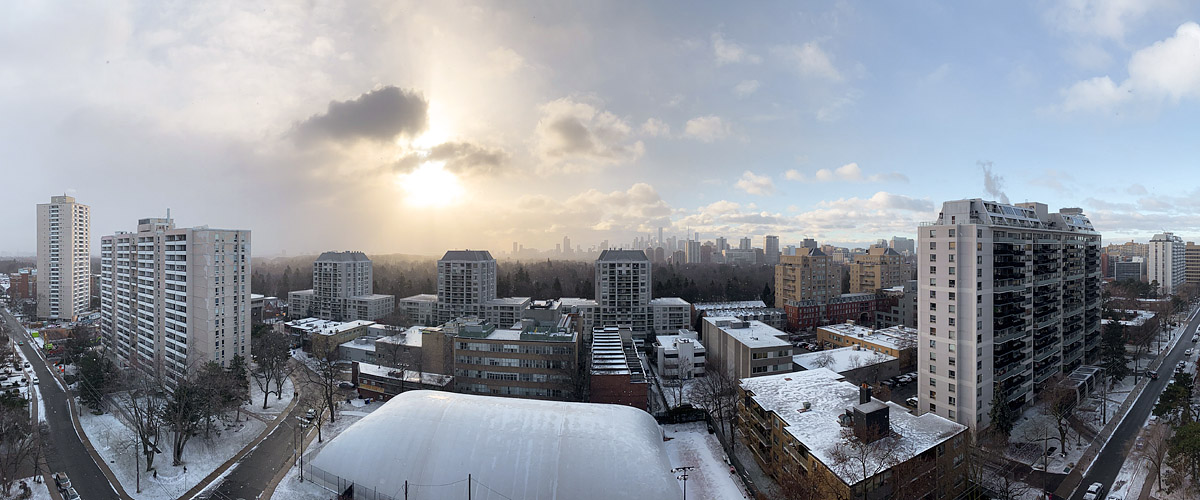 Broken cloud with the sun behind it, the skyline soft and fresh snow on every roof and branch.