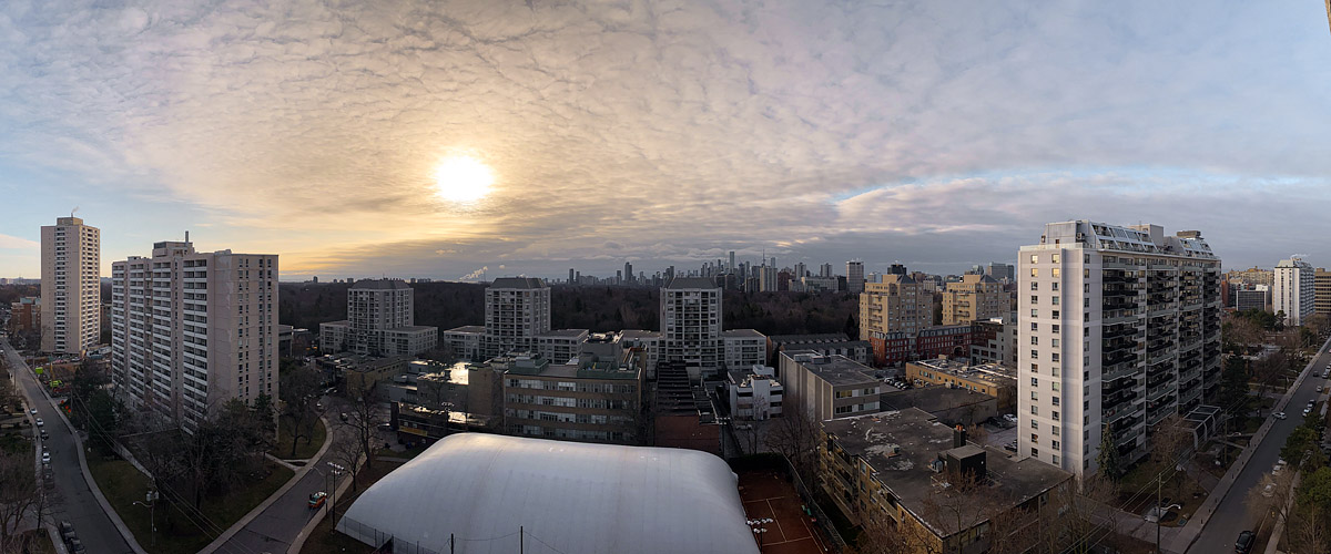 A fine rippled cloud deck covers the sky with the sun glowing through it and the skyline clear below.