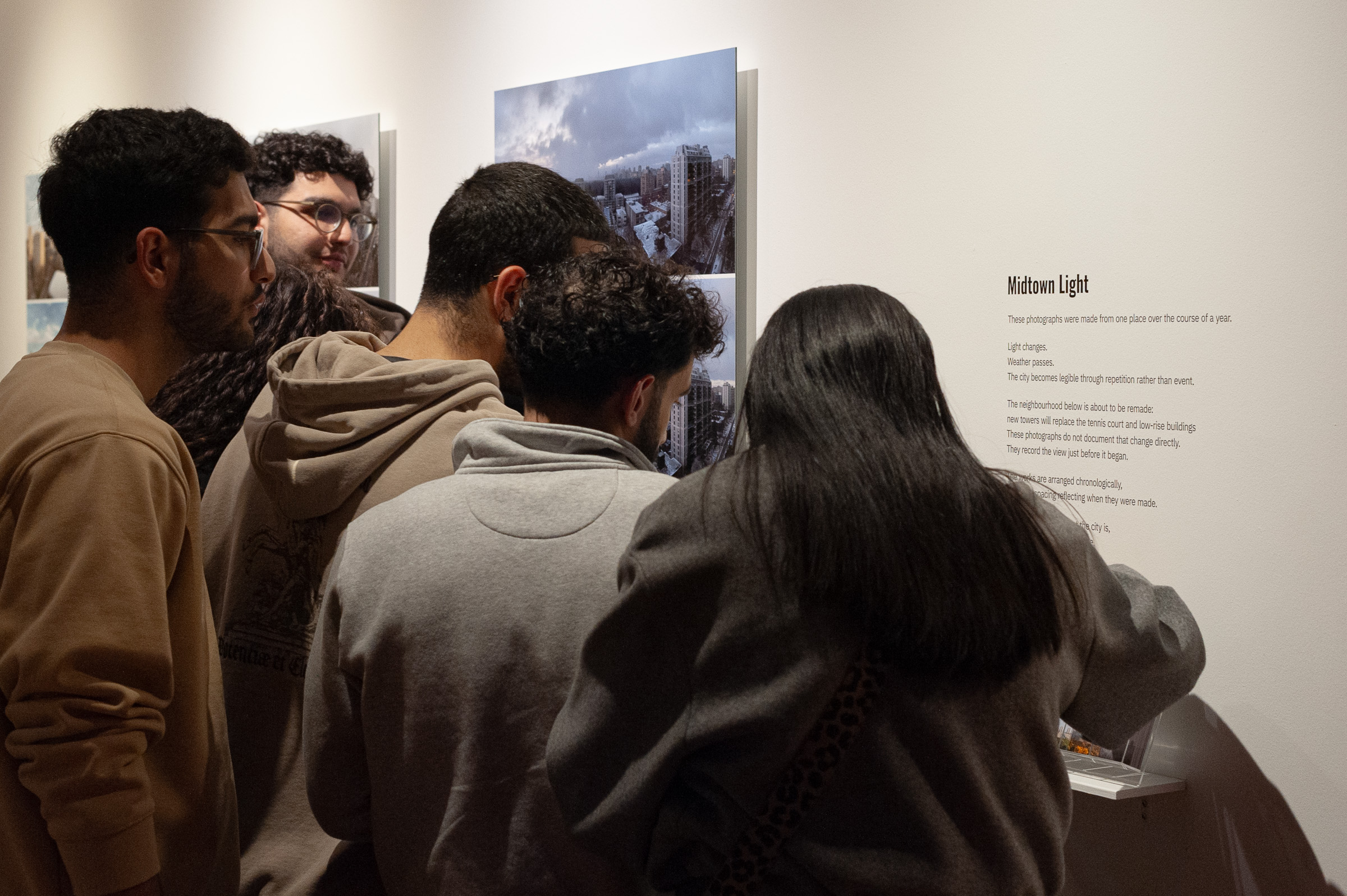 A group of visitors gathers at the Midtown Light wall text.