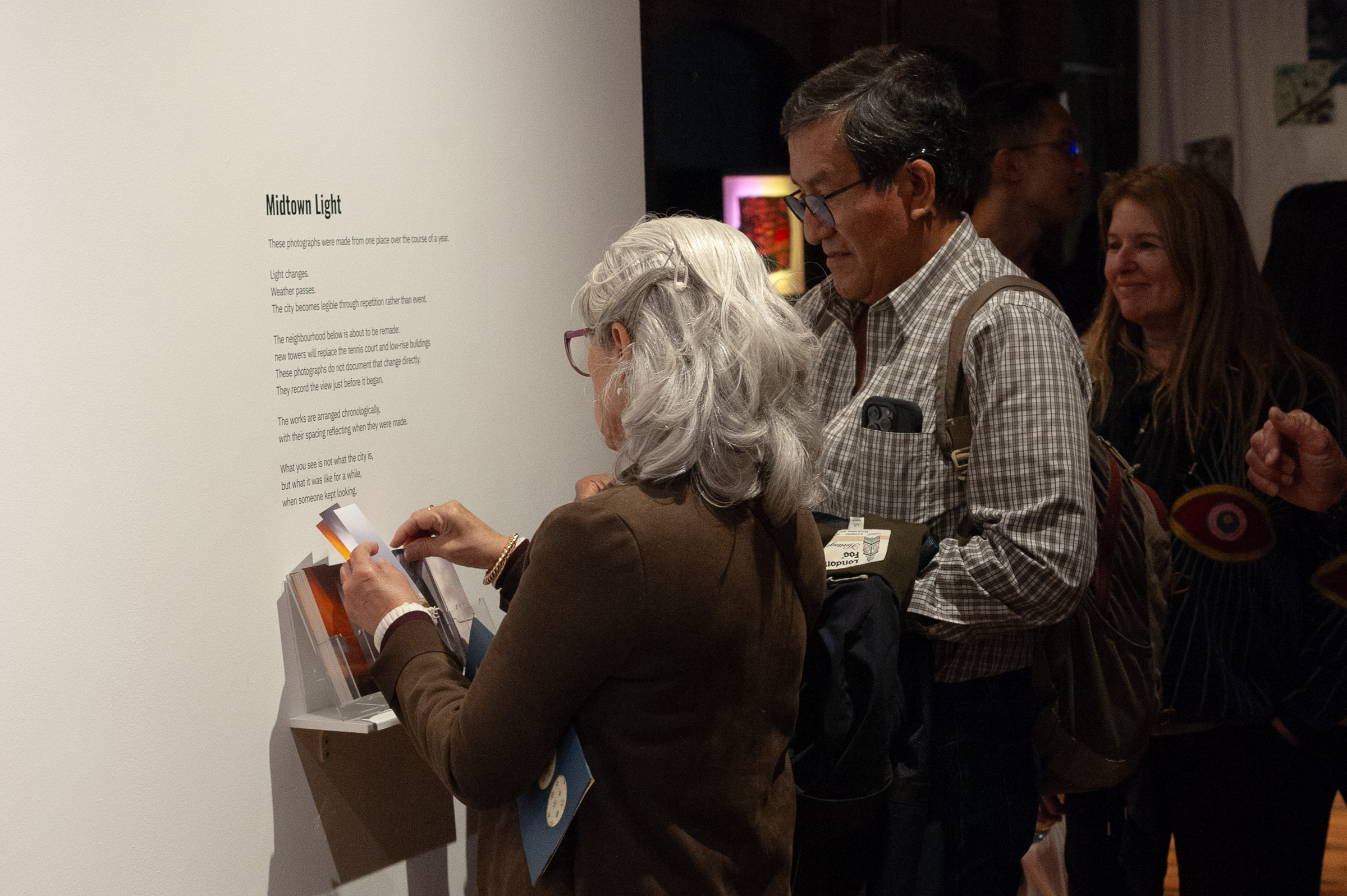 A visitor takes bookmarks from the rack beside the wall text.