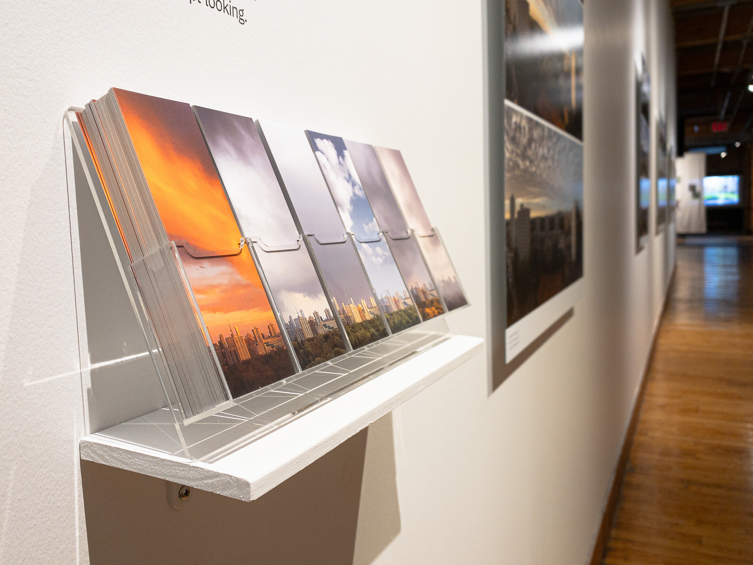 Close view of the bookmark holder with six bookmark designs, the exhibition wall receding behind it.