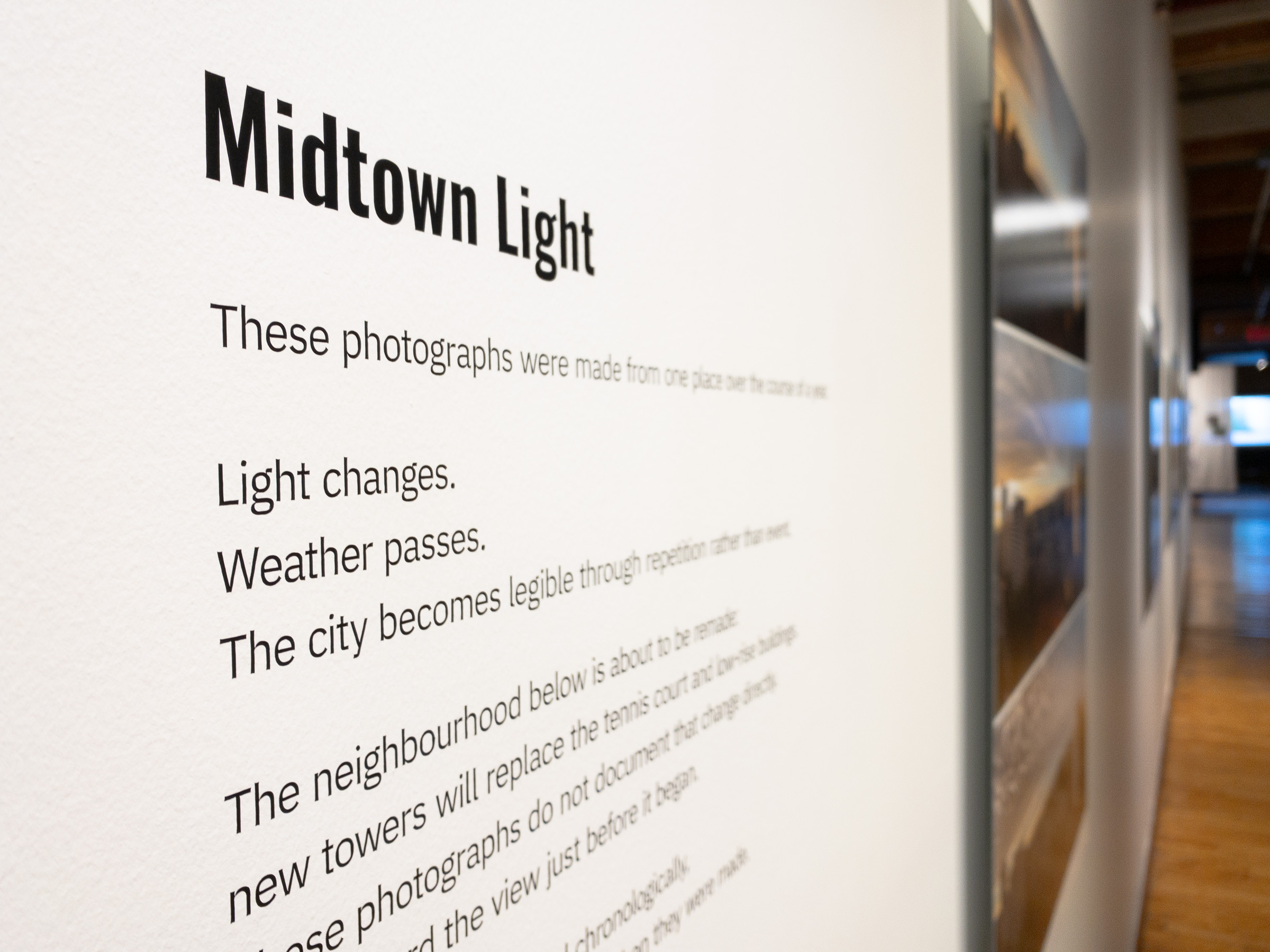 Oblique close view of the Midtown Light wall text, in shallow focus, with the corridor beyond.